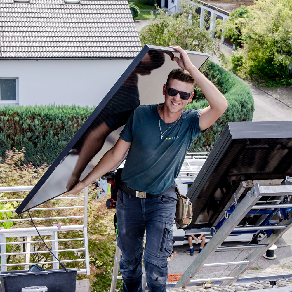Lachender Mitarbeiter trägt eine Photovoltaikanlage