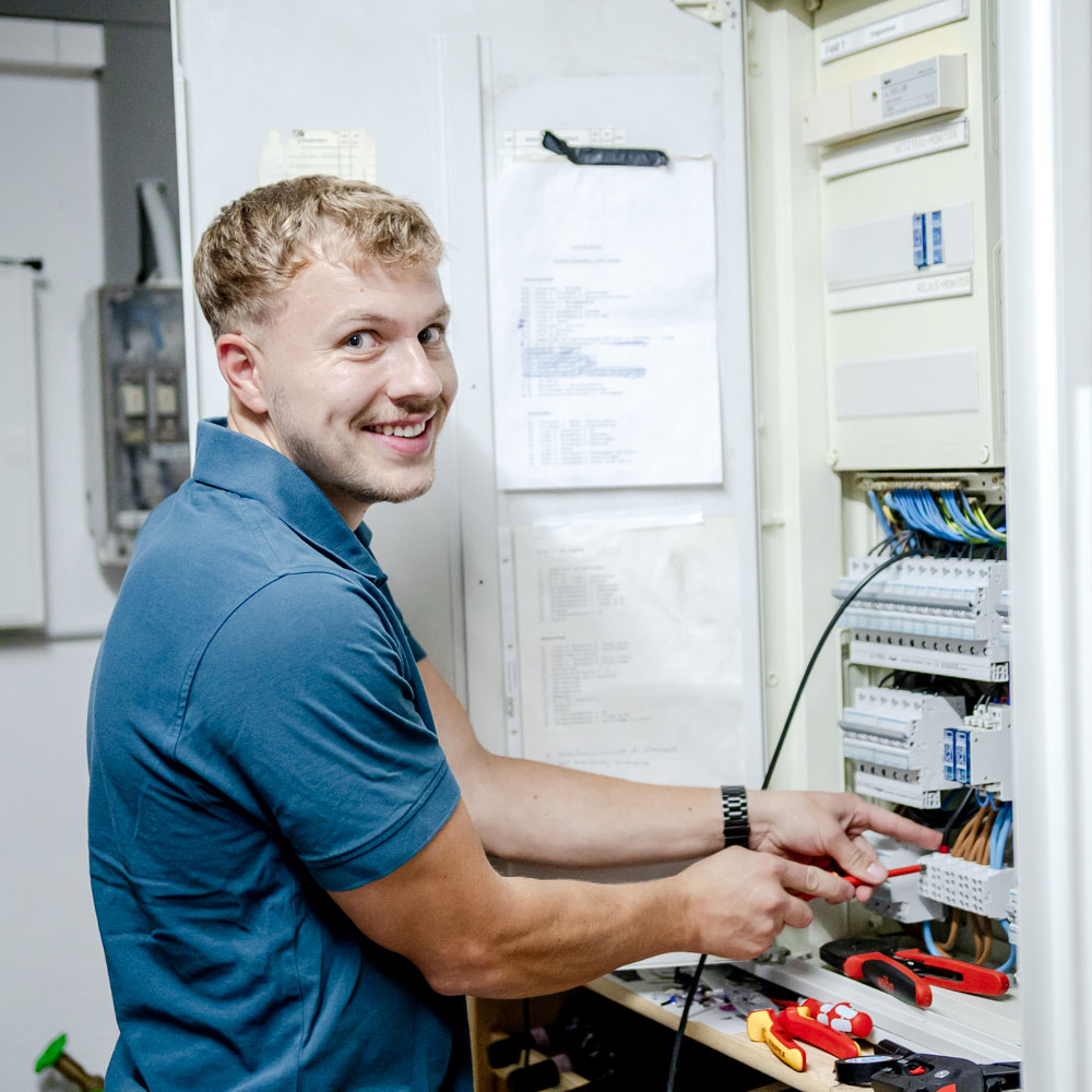Lachender Mitarbeiter am Schaltschrank